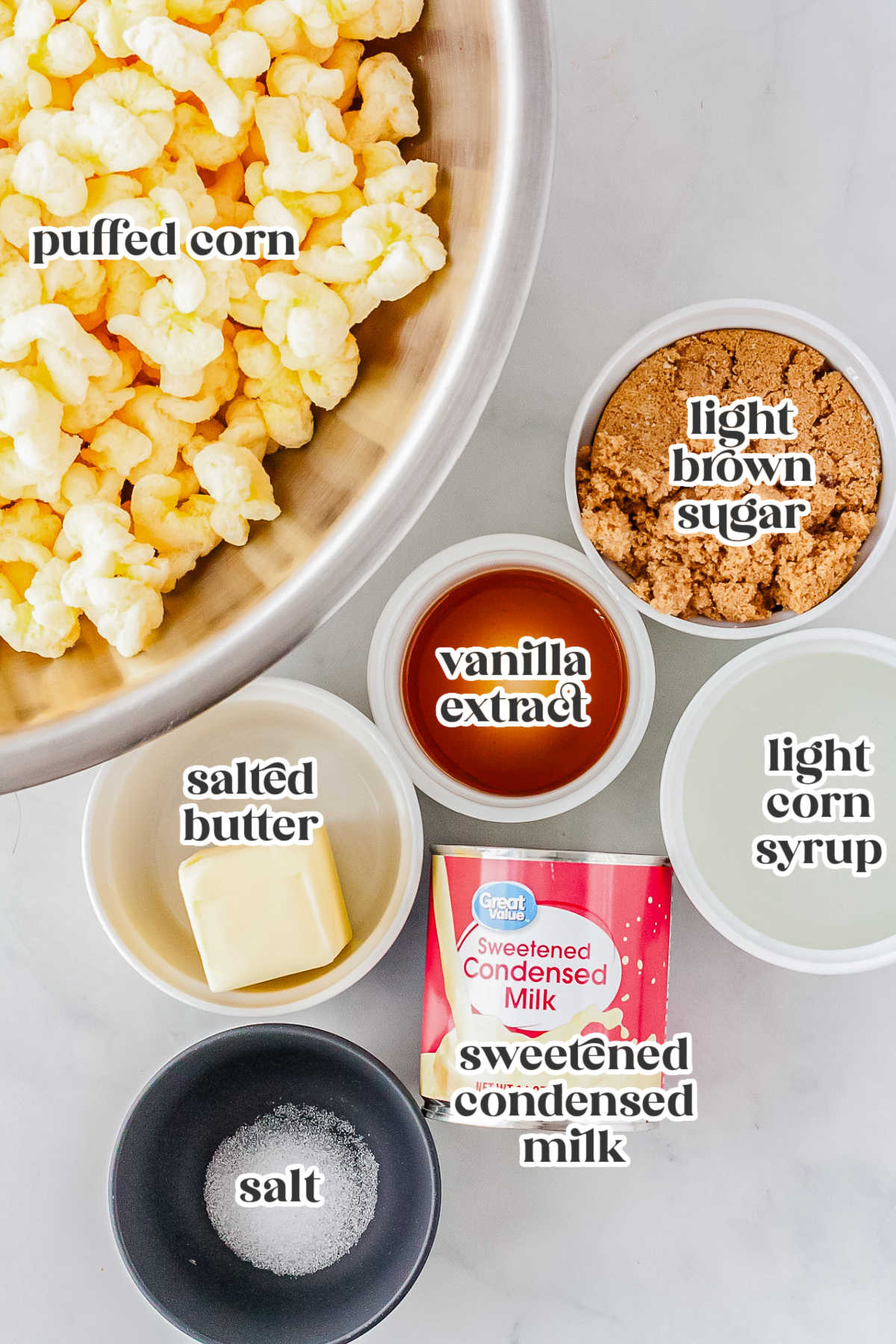 Flat lay of puffed corn and measured ingredients including brown sugar, butter, corn syrup, condensed milk, salt and vanilla extract arranged on a countertop.