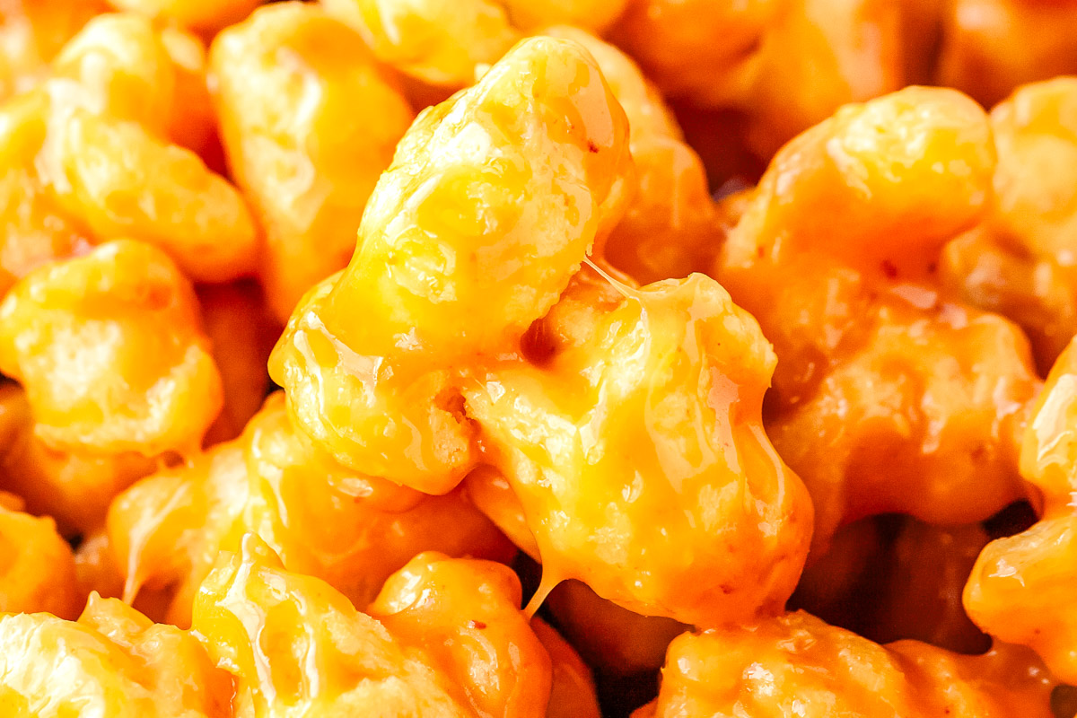 Extreme close up of caramel puffed corn showing the shiny golden caramel coating and airy texture.