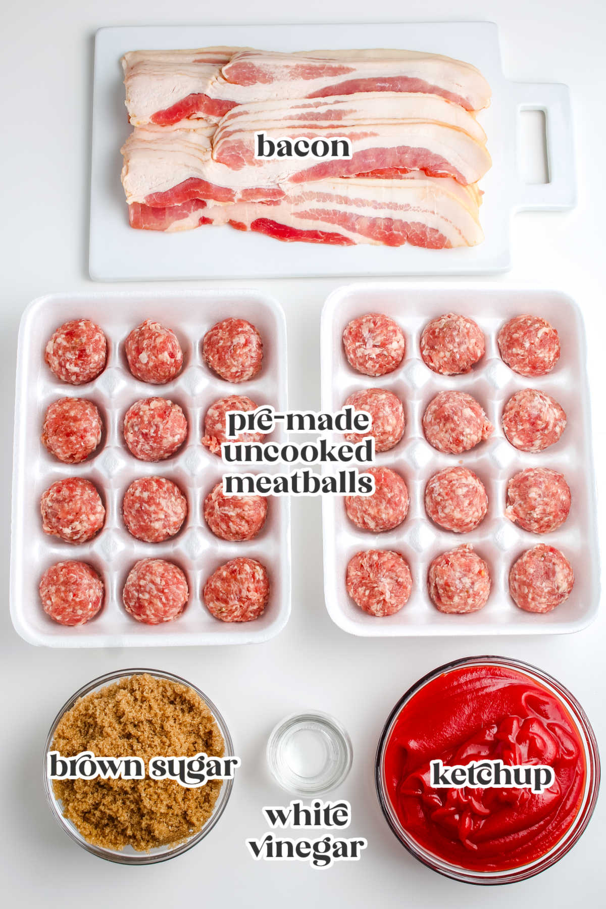 Ingredients for bacon wrapped meatballs laid out on a white surface with text labels: bacon, pre-made uncooked meatballs, brown sugar, white vinegar, and ketchup.