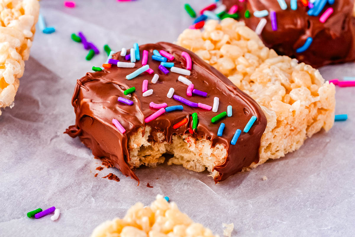 Chocolate dipped Rice Crispy treat with a bite taken out showing the chewy center.