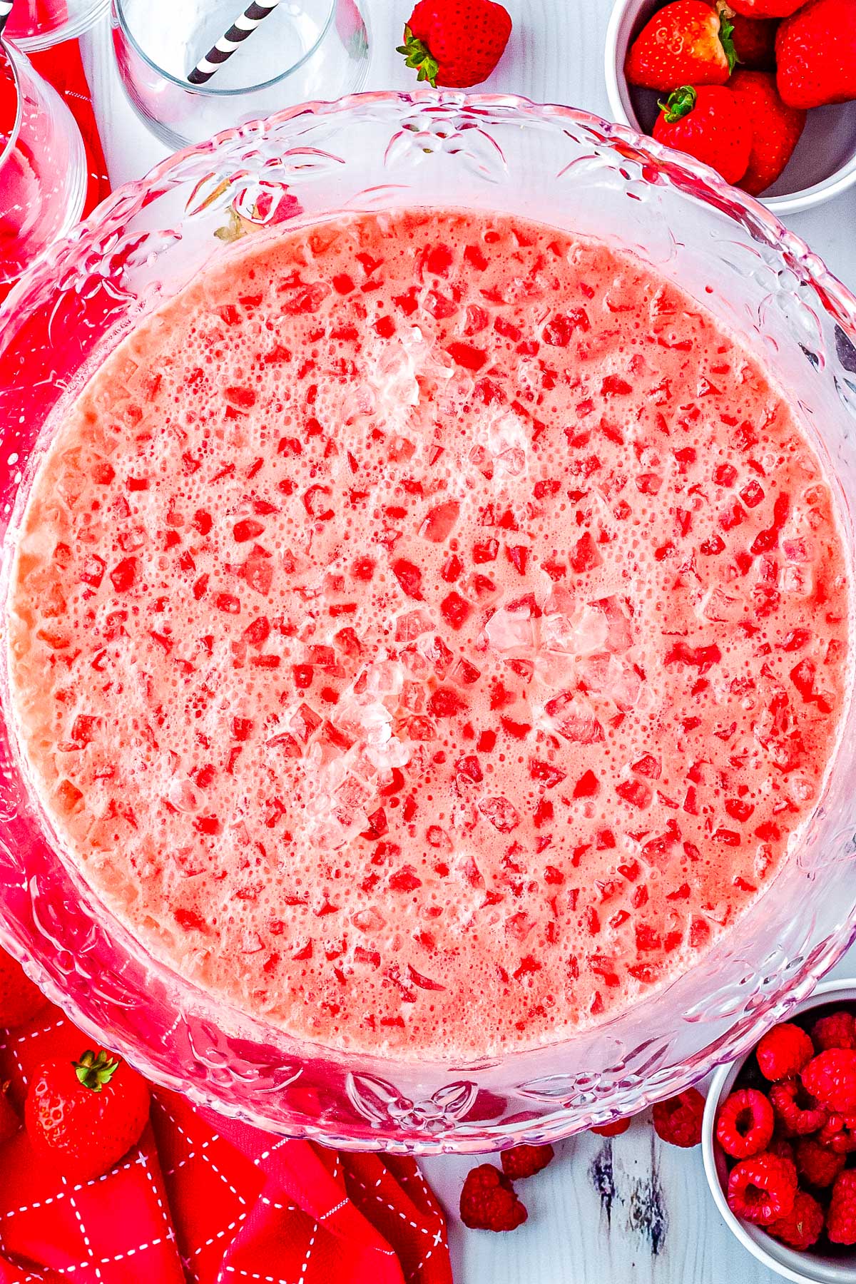 Close up overhead photo of a large punch bowl filled with creamy pink Polar Punch and crushed ice.