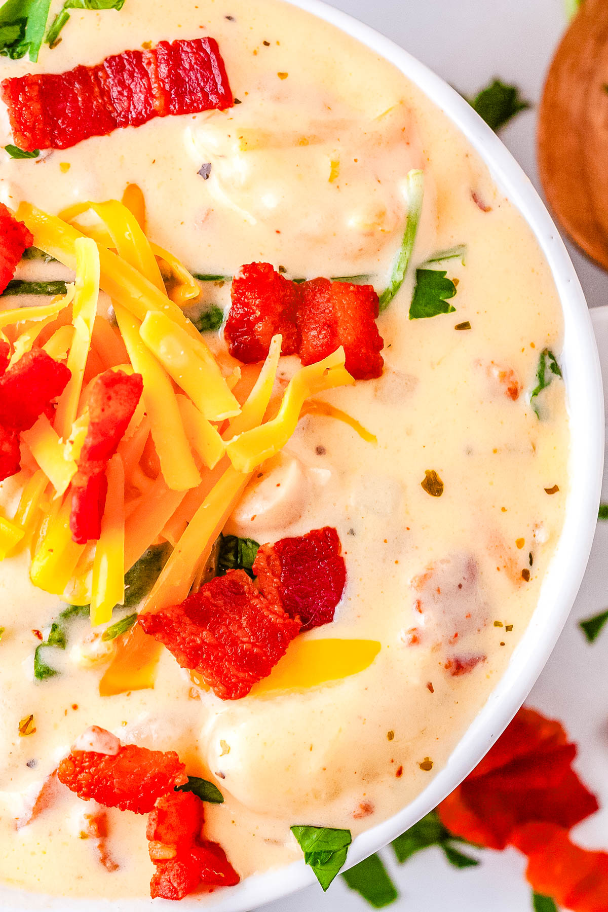 A close-up overhead view of the soup highlighting the melted cheddar cheese, crispy bacon pieces, and fresh parsley garnish.