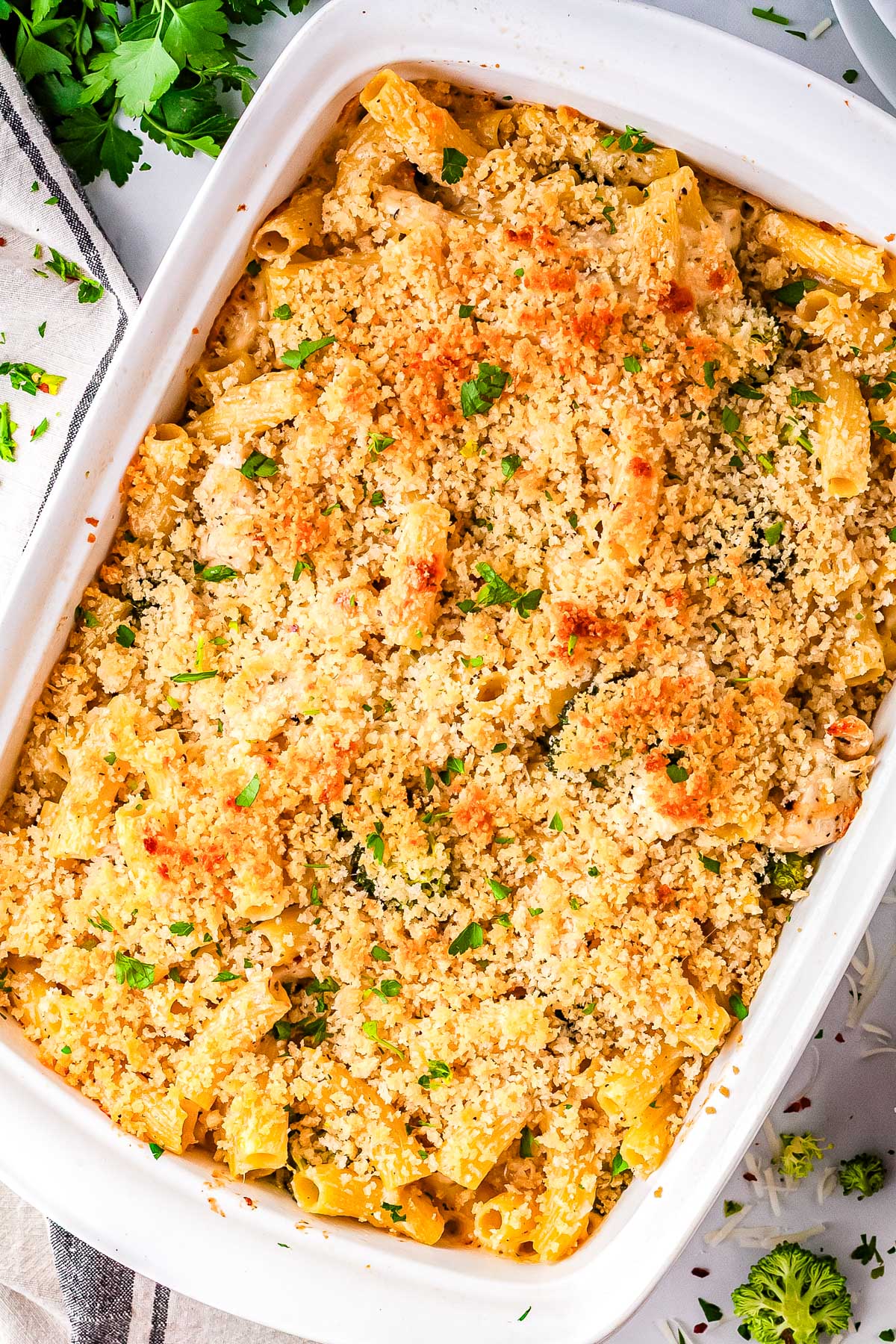 Alfredo chicken broccoli bake in a white baking dish topped with golden panko breadcrumbs and fresh parsley.