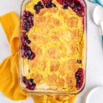 Golden baked blueberry lemon dump cake in a glass baking dish with crisp topping and bubbling edges.