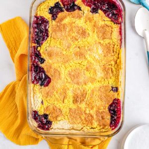 Golden baked blueberry lemon dump cake in a glass baking dish with crisp topping and bubbling edges.