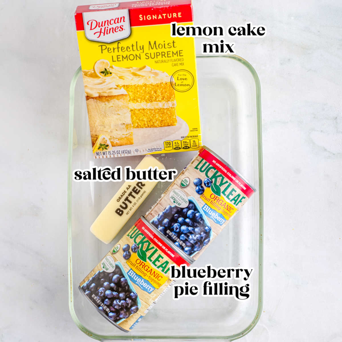 Lemon cake mix, blueberry pie filling, and sliced butter arranged in a baking dish for blueberry lemon dump cake.