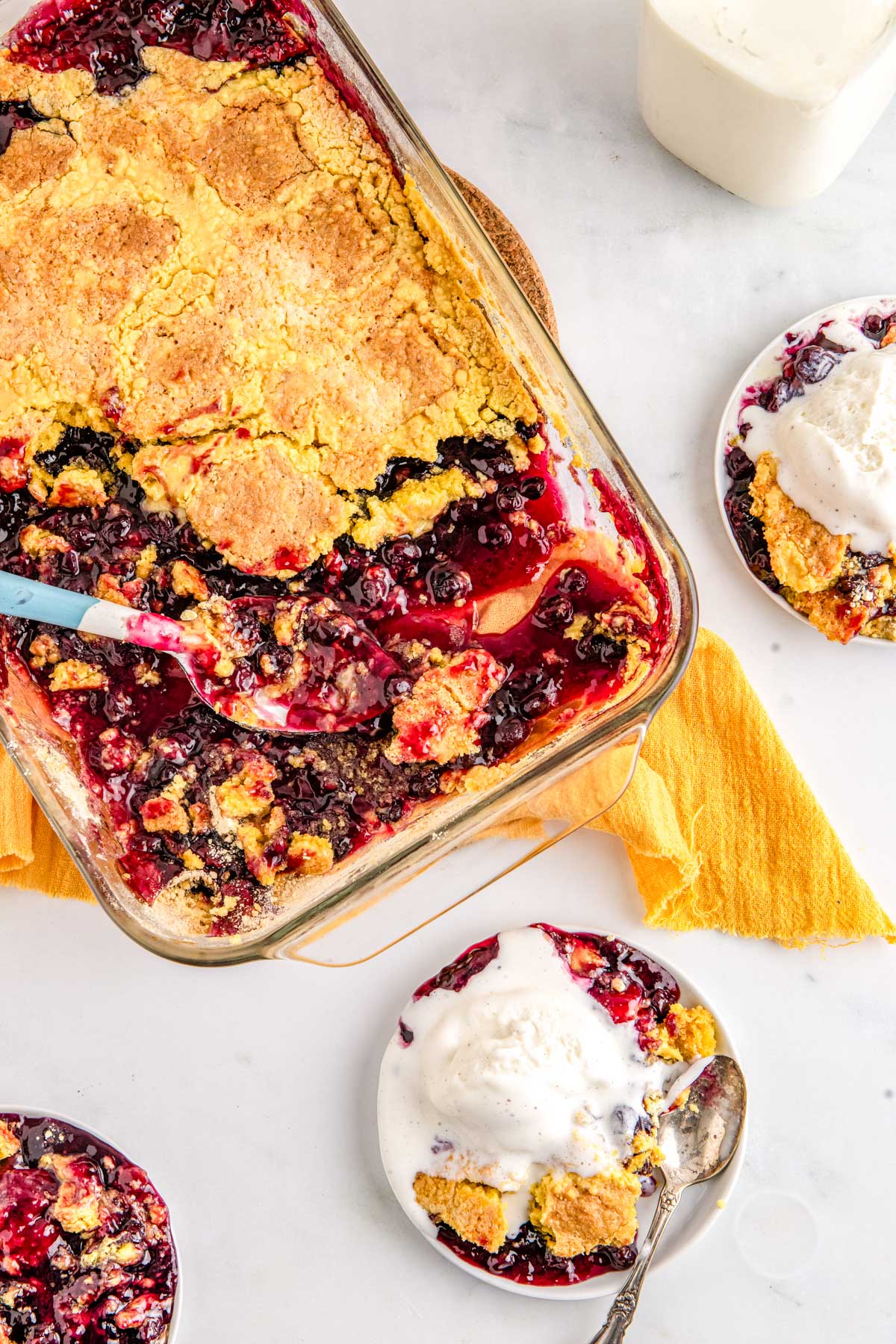 Blueberry lemon dump cake served warm with vanilla ice cream and visible jammy blueberry filling.