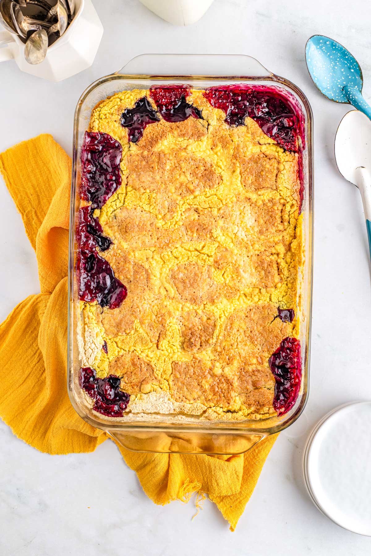Golden baked blueberry lemon dump cake in a glass baking dish with crisp topping and bubbling edges.