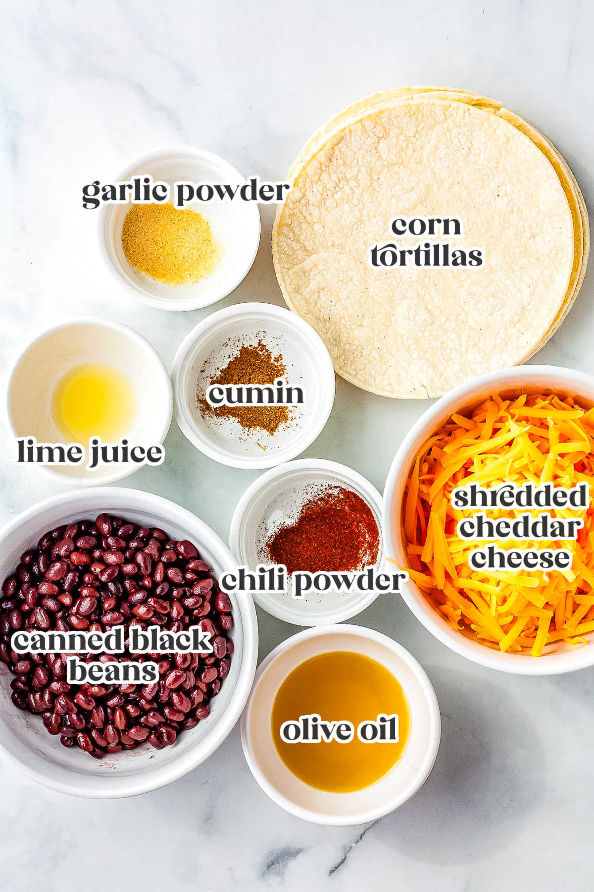 Ingredients for crispy black bean tacos including canned black beans, corn tortillas, cheddar cheese, lime juice, cumin, chili powder, garlic powder, and olive oil.