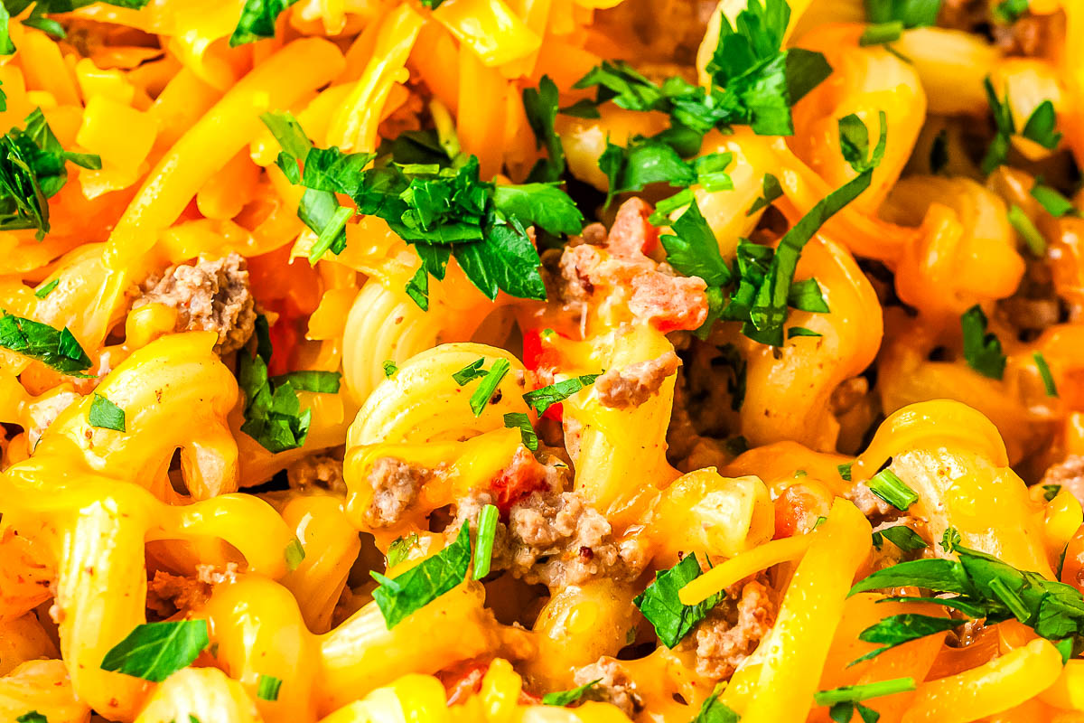 Close up of creamy Rotel pasta showing melted cheddar coating cavatappi with ground beef and diced tomatoes.
