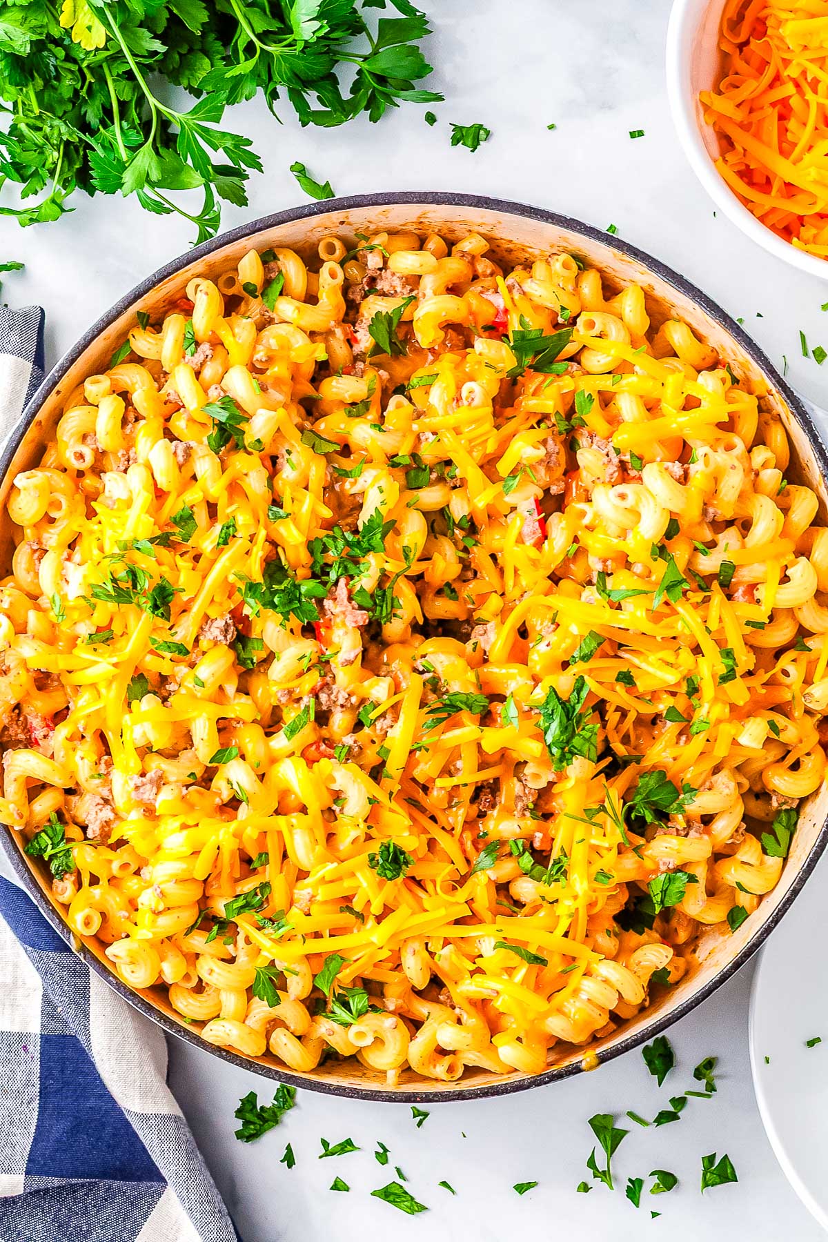Overhead view of creamy Rotel pasta in a skillet topped with melted cheddar cheese and chopped parsley.