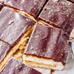 Overhead view of sliced chocolate eclair ice cream cake topped with chocolate ganache and graham cracker crumbs.