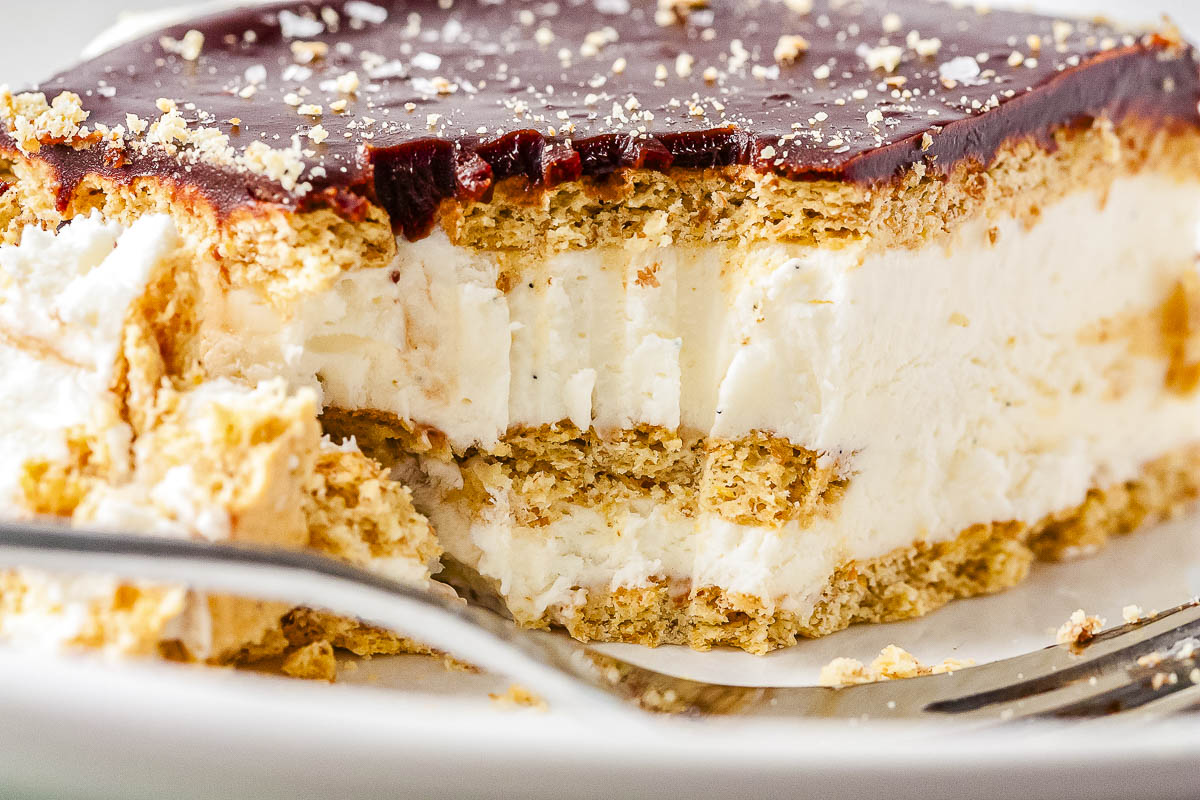 Close up of chocolate eclair ice cream cake with layers of graham crackers, vanilla bean ice cream filling, and glossy chocolate ganache.