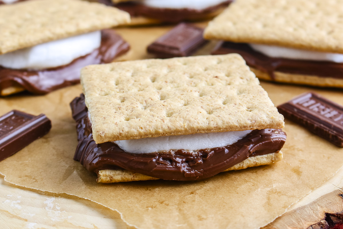 Close up of a grilled s'more with melted milk chocolate and a soft marshmallow between graham crackers.