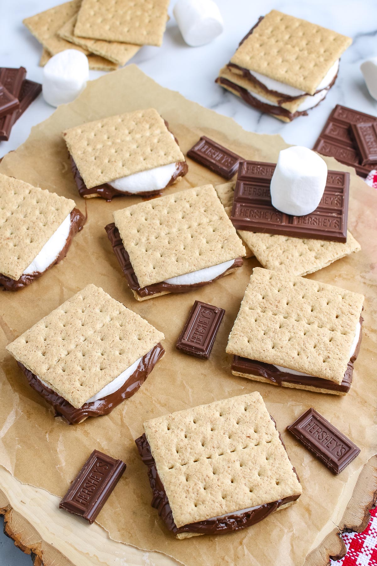 Overhead view of grilled s'mores with melted chocolate and marshmallows arranged on parchment paper.