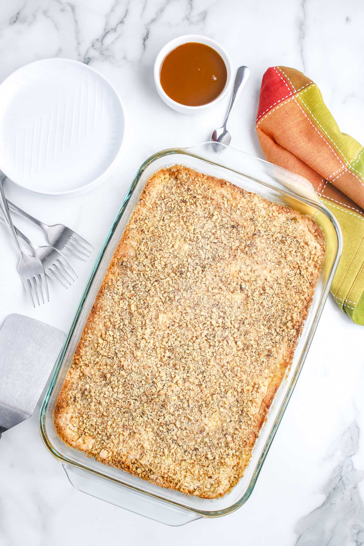 An overhead view of a freshly baked apple dump cake in a glass baking dish with a golden brown pecan crust.